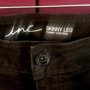 INC skinny leg tummy control jeans, black with white stripes down the sides.